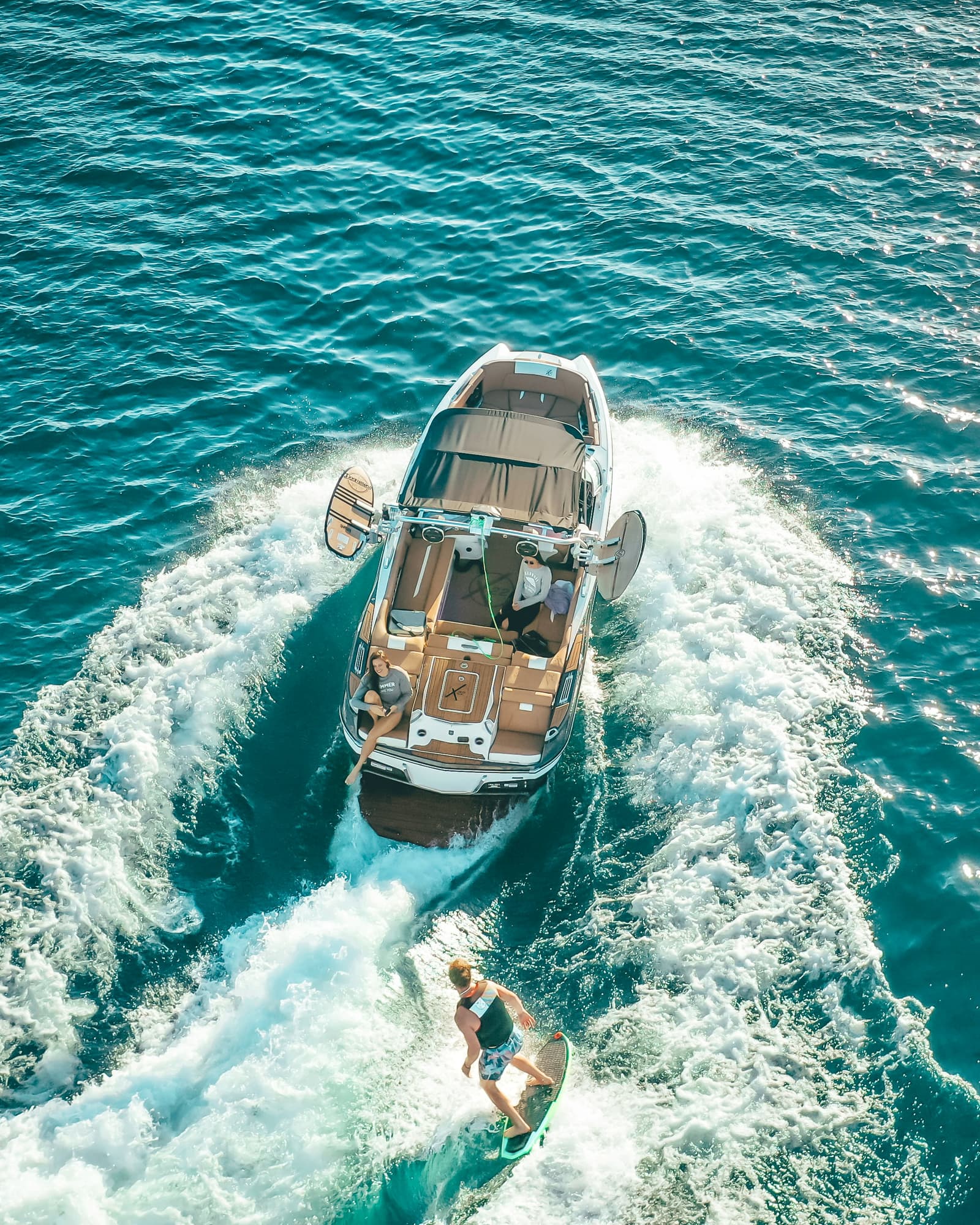 Aerial view of luxury sport boat with wakesurfer behind it