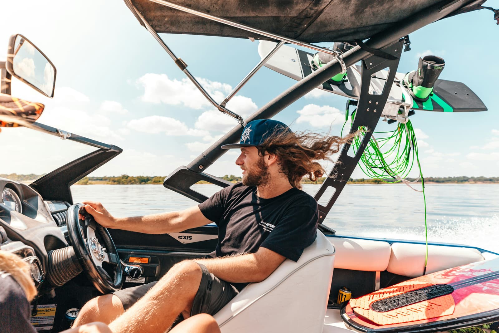 Man driving a wakeboard boat on the water on a sunny day