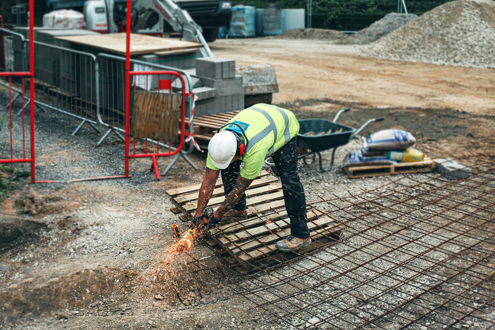 Construction worker in safety vest cutting rebar on a building site with sparks flying