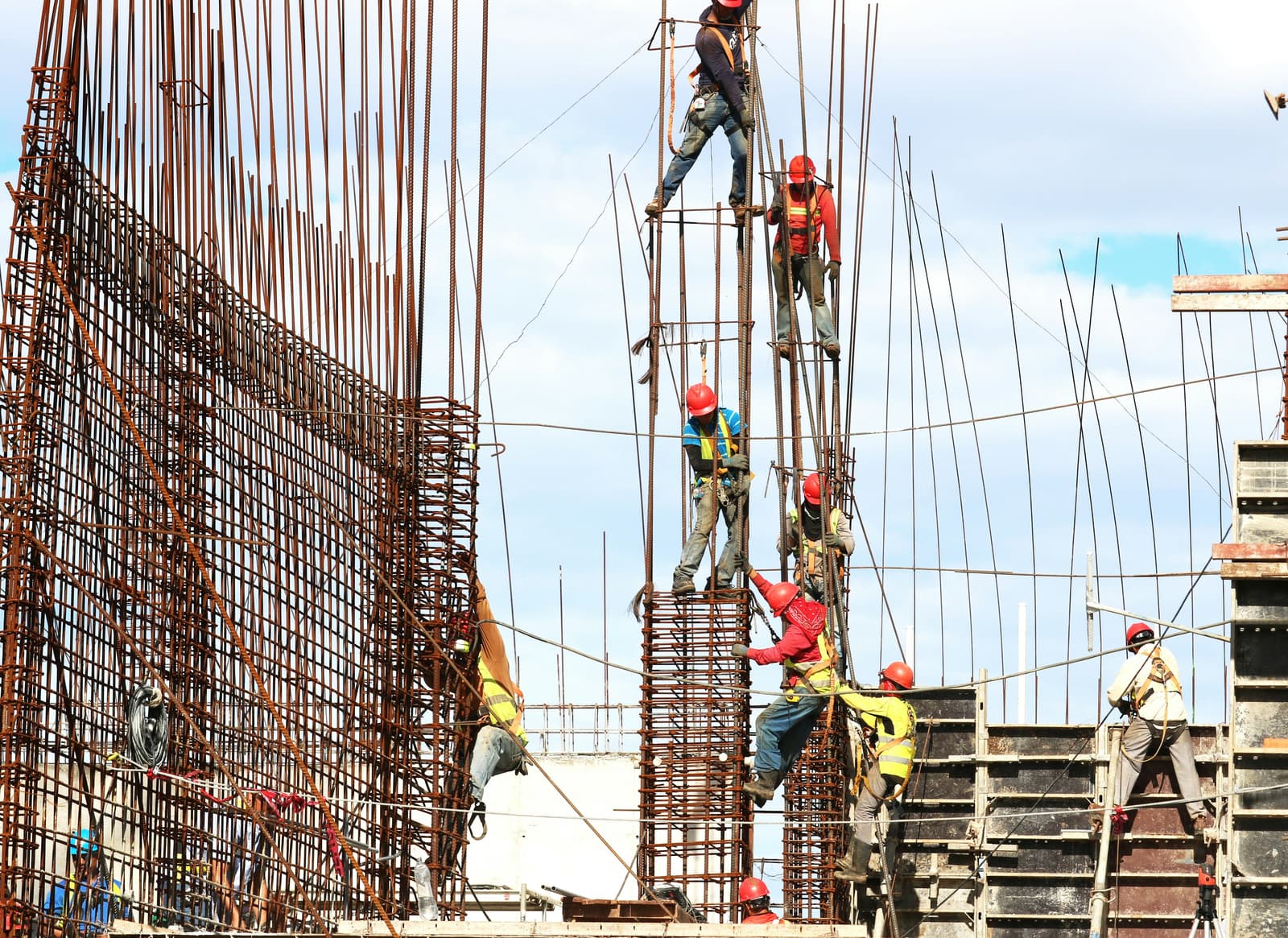 Construction workers assembling steel rebar reinforcement on a large building project