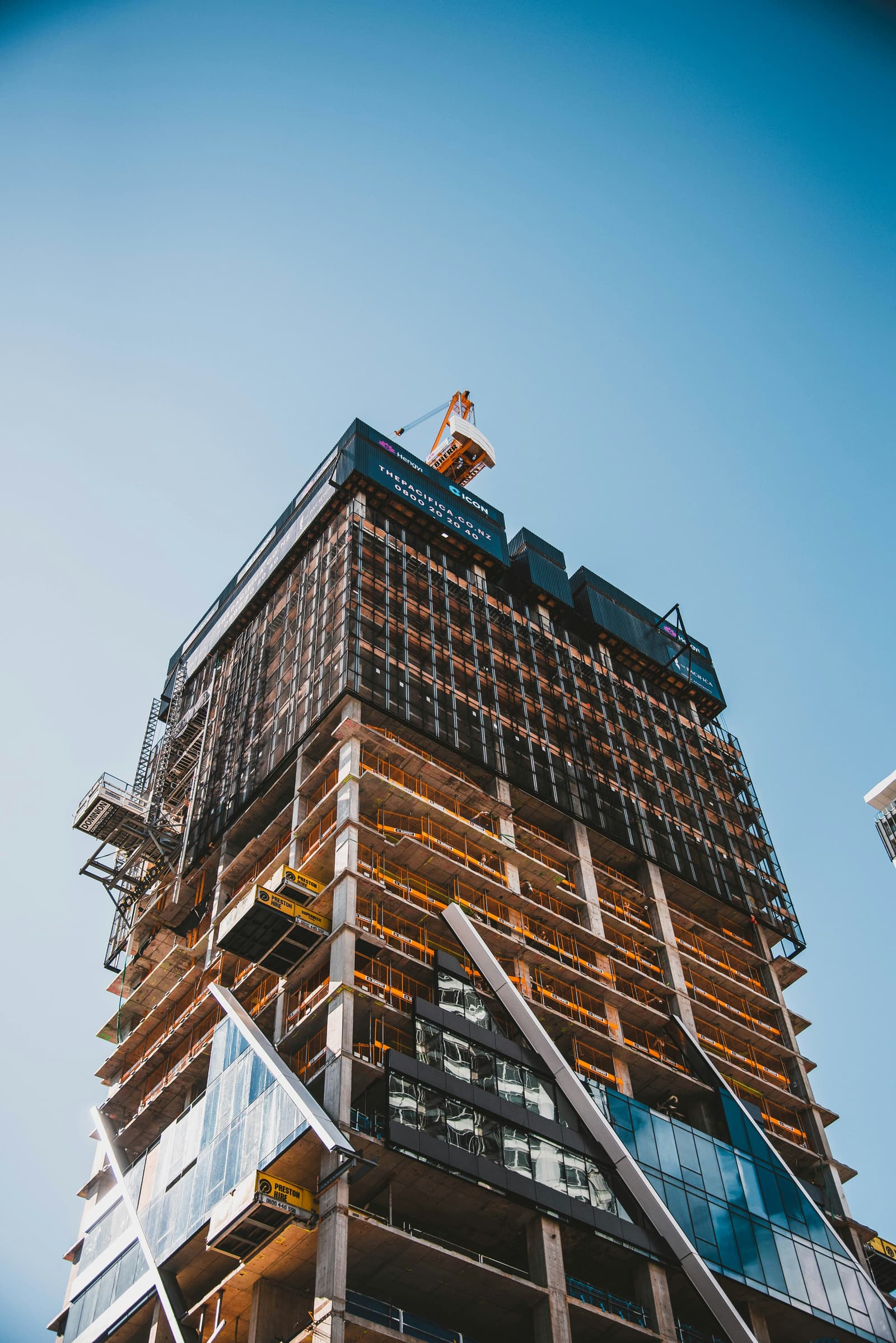 High-rise building under construction viewed from below against a clear blue sky