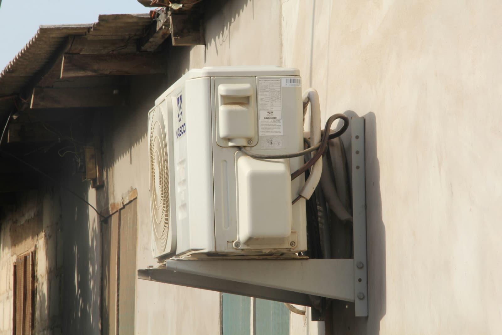 Wall-mounted air conditioning outdoor condenser unit on the side of a residential building