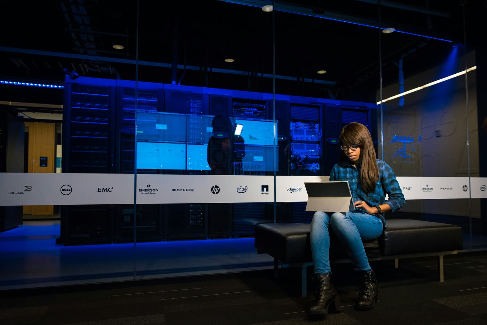 Woman working on laptop in front of illuminated data center servers