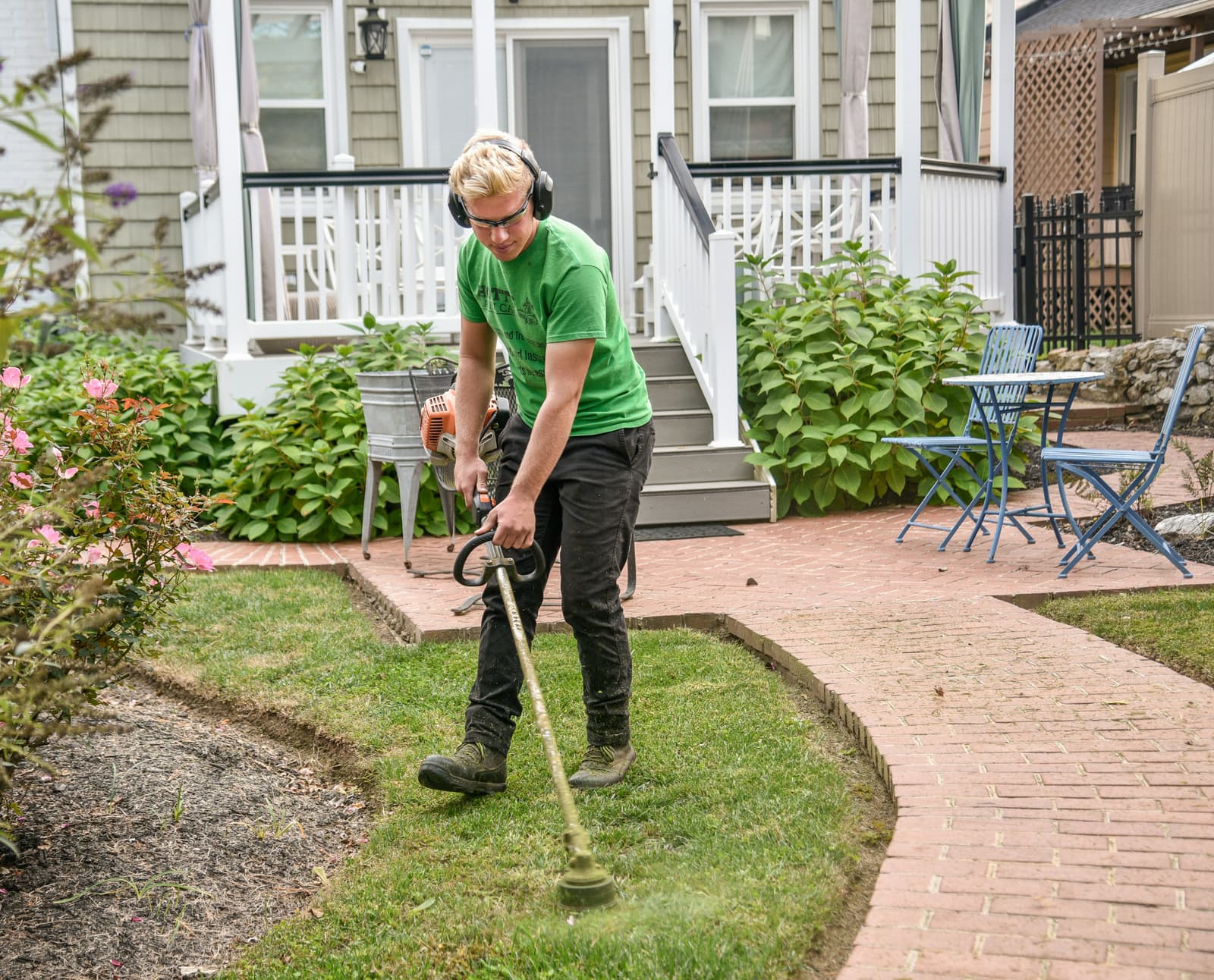 Landscaper using a string trimmer to edge a lawn
