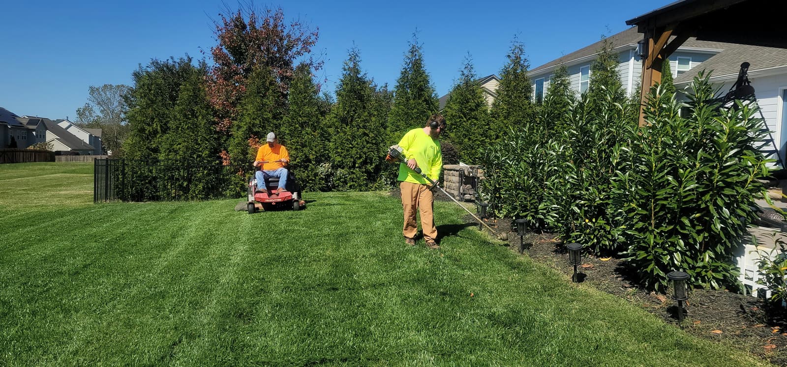 Landscaping crew mowing and trimming a large residential property