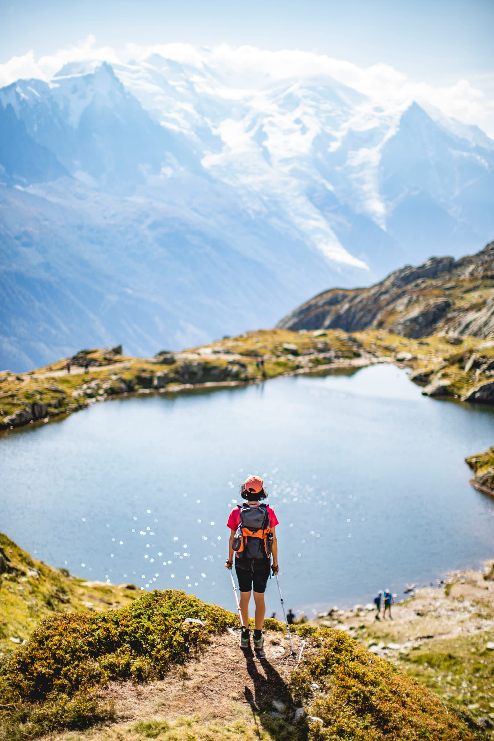 Hiker gazing at an alpine lake and snow-capped mountains