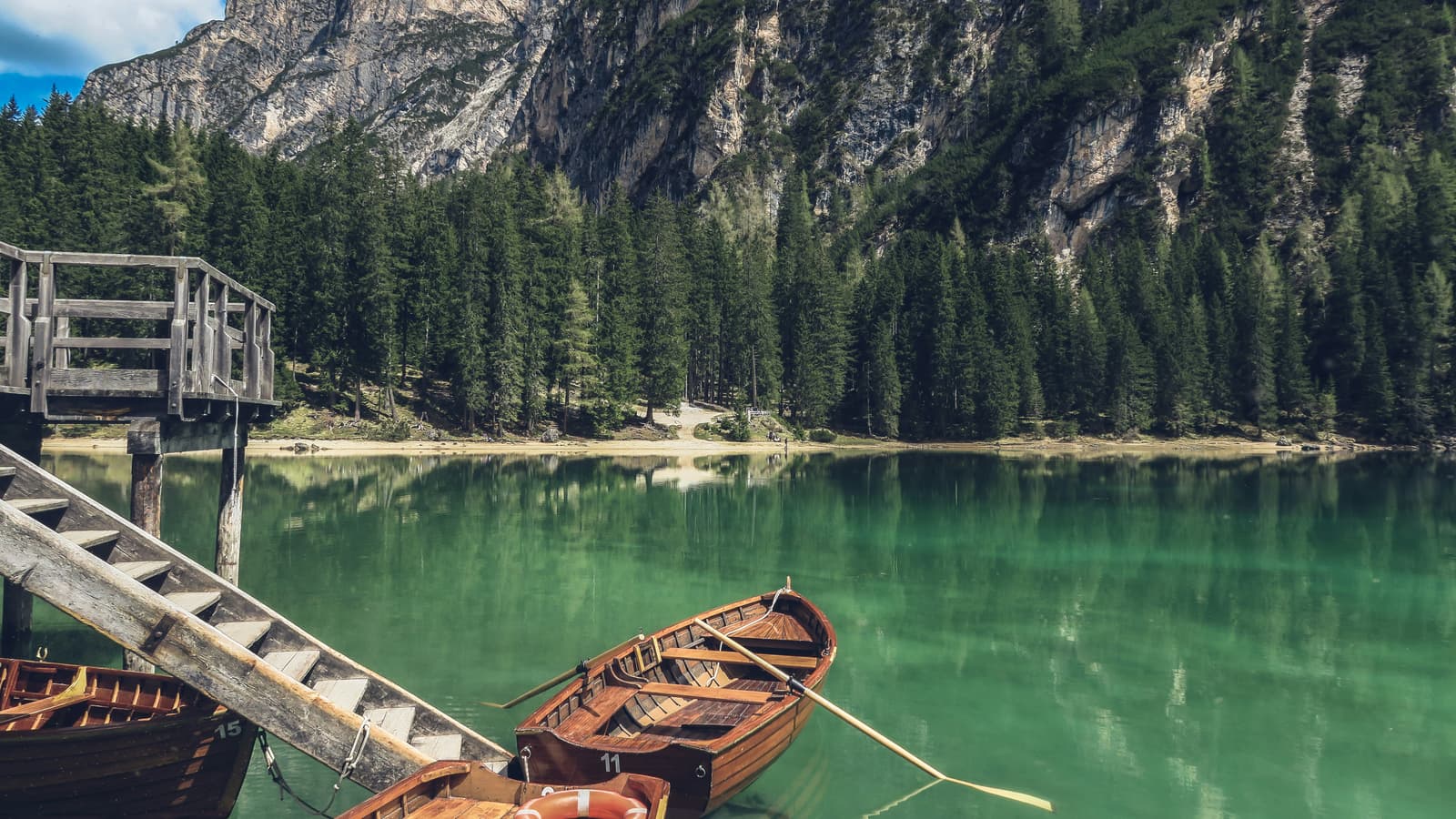 Wooden boats docked on turquoise alpine lake surrounded by mountains