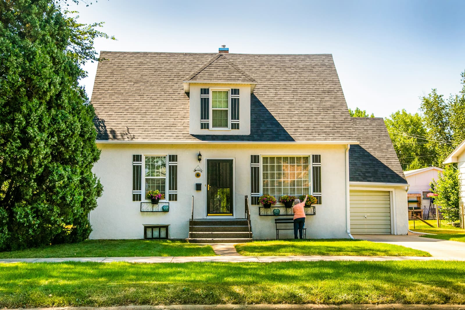 Classic cottage-style home with white siding and green lawn